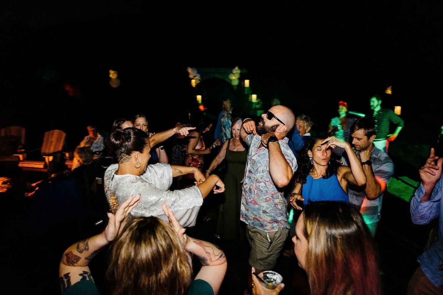 A lively group of people dancing and enjoying a party in a dimly lit outdoor space.