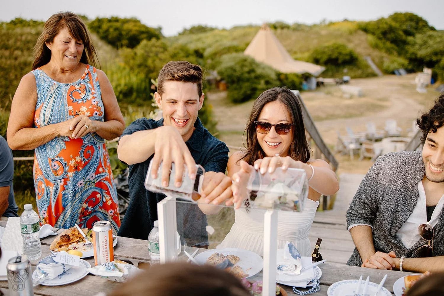 A group of friends at a picnic table enthusiastically participate in a fun activity outdoors.
