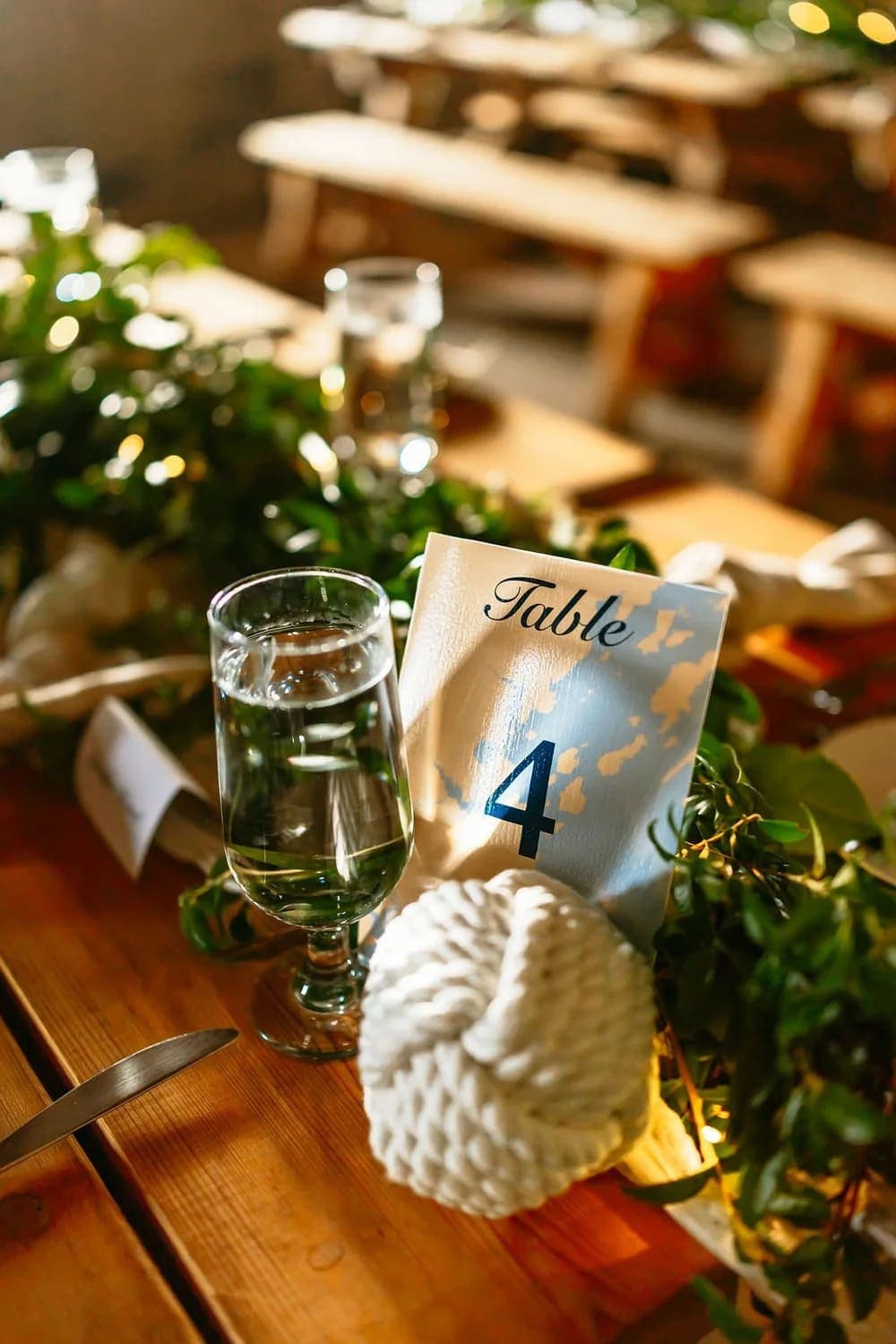 A table setting featuring a number "4" card, a glass of water, and decorative greenery.