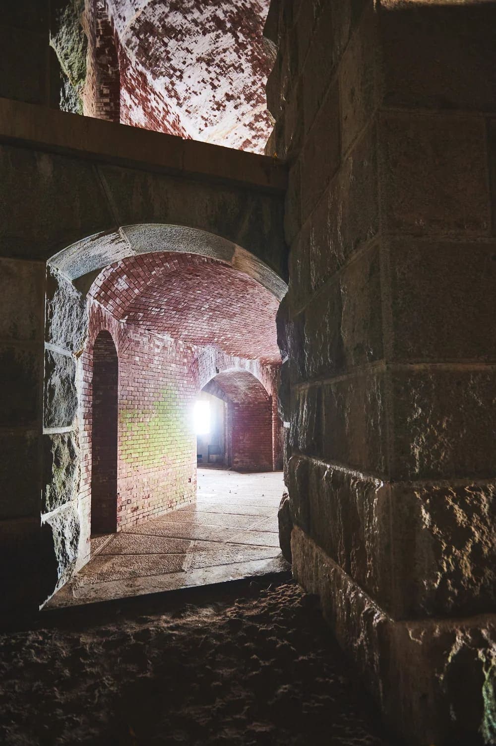 An arched passage leads to a dimly lit brick interior with stone walls.