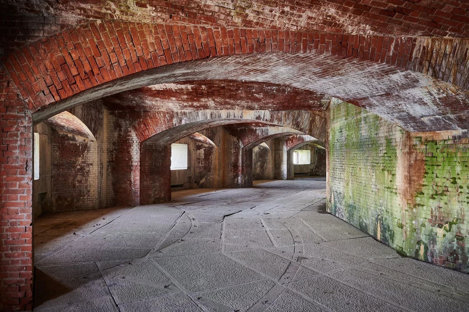 Abandoned brick interior with arched ceilings and weathered walls.