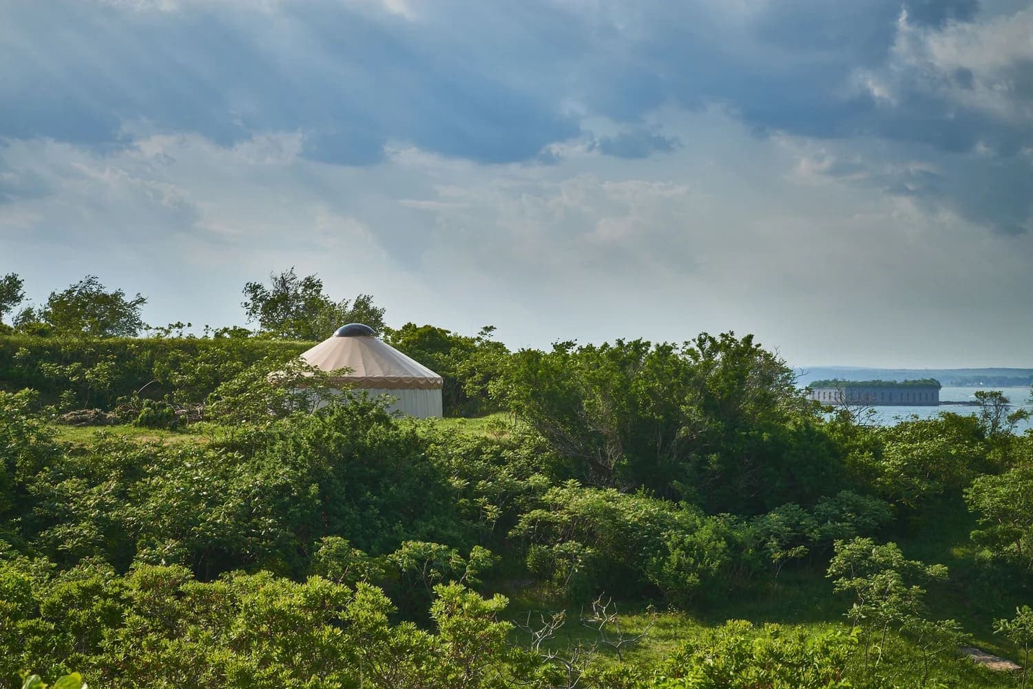 A yurt nestled in lush greenery with a misty sky above.