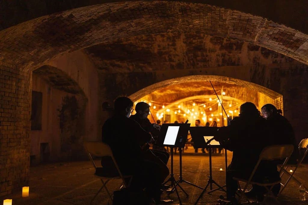 A group of musicians performs in a dimly lit archway surrounded by glowing candles.