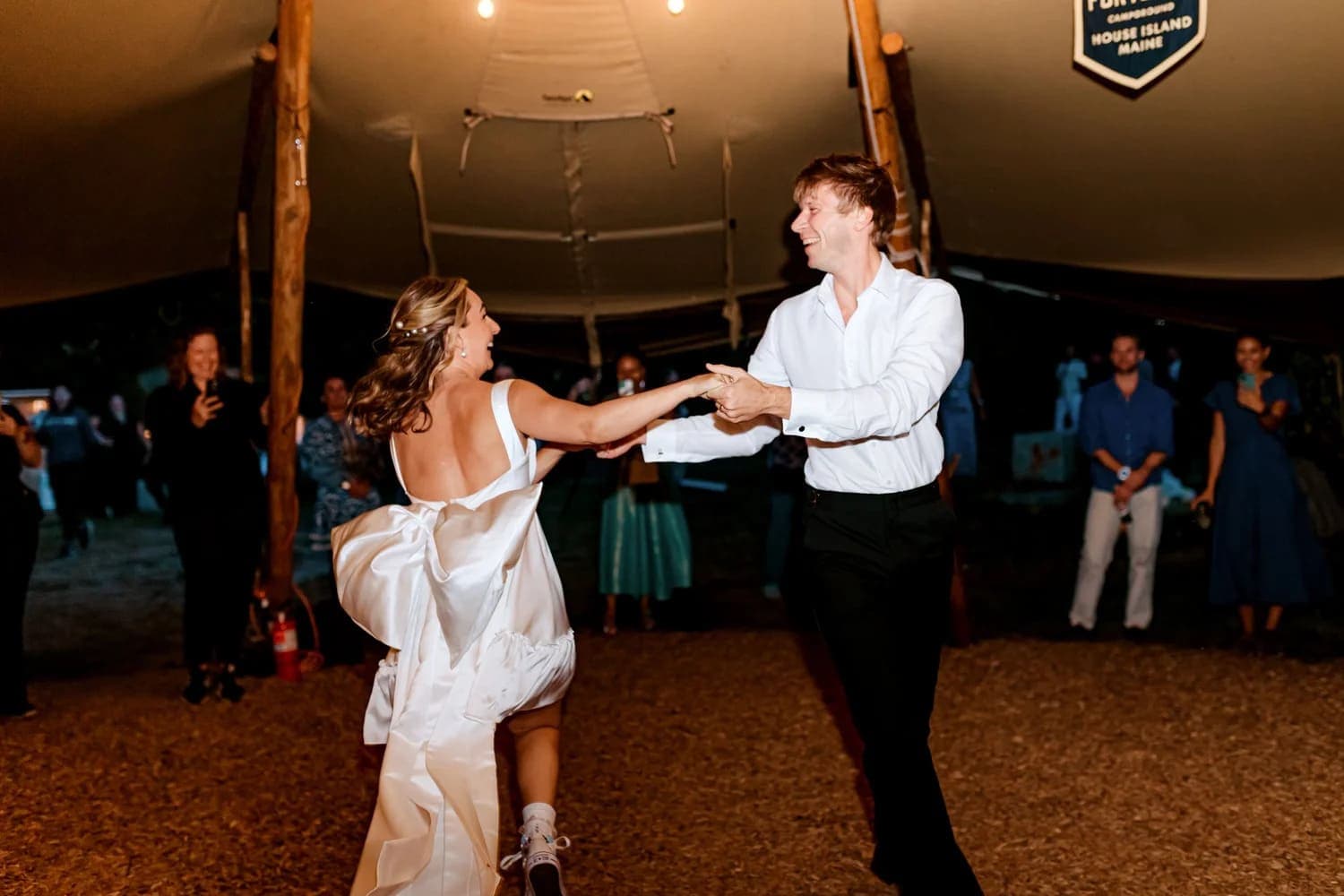 A couple joyfully dances together under soft lights at a festive outdoor event.