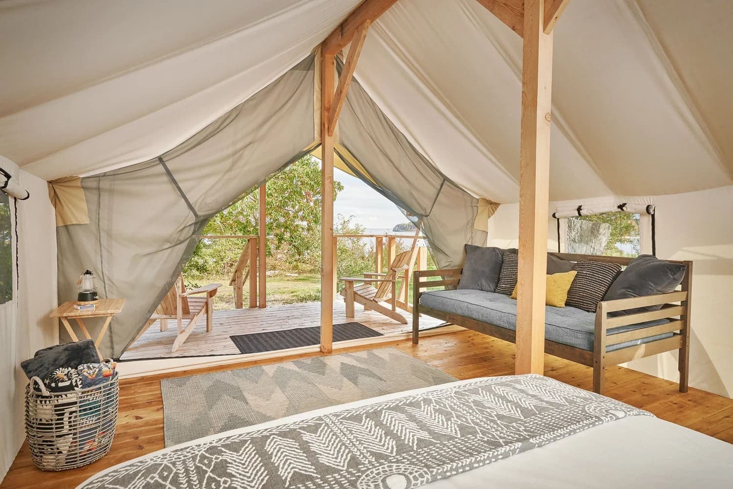 A cozy, tent-like interior with wooden furnishings and an open view of greenery.